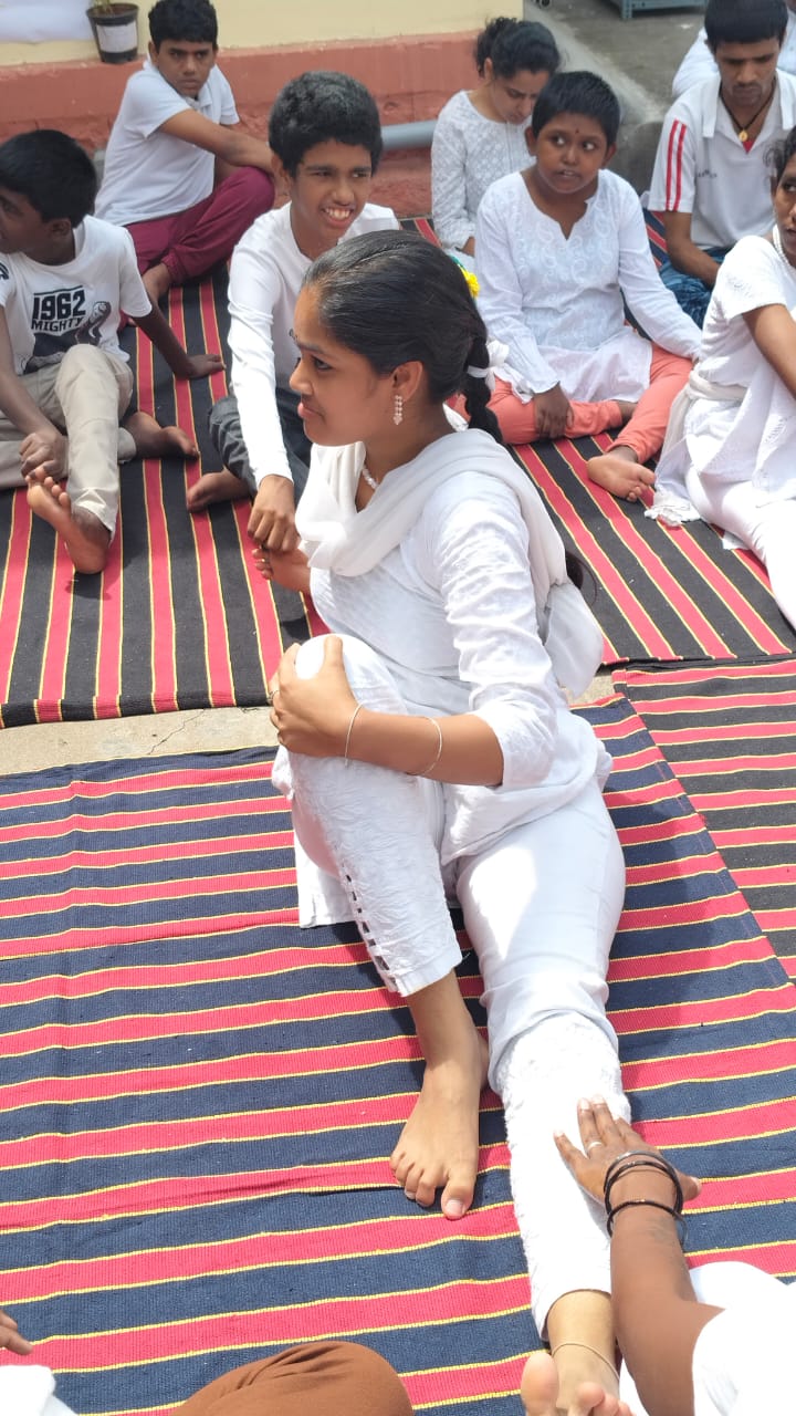 Students sitting outdoors on mats during a group activity